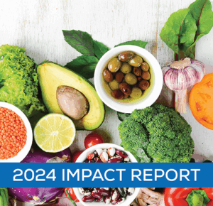Colorful assortment of fresh vegetables and legumes including avocado, lime, broccoli, olives, garlic, and beans arranged on a white wooden surface. A blue banner across the bottom reads ‘2024 Impact Report.’