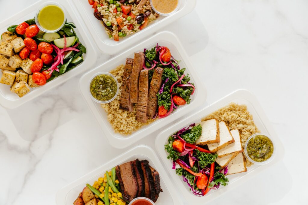 Overhead view of Mealogic prepared meal trays featuring a variety of proteins, grains, and vegetables
