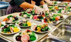 Close up of plates of colorful fresh salads in a commercial kitchen.